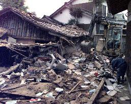 Power shovel clears collapsed houses after strong quake
